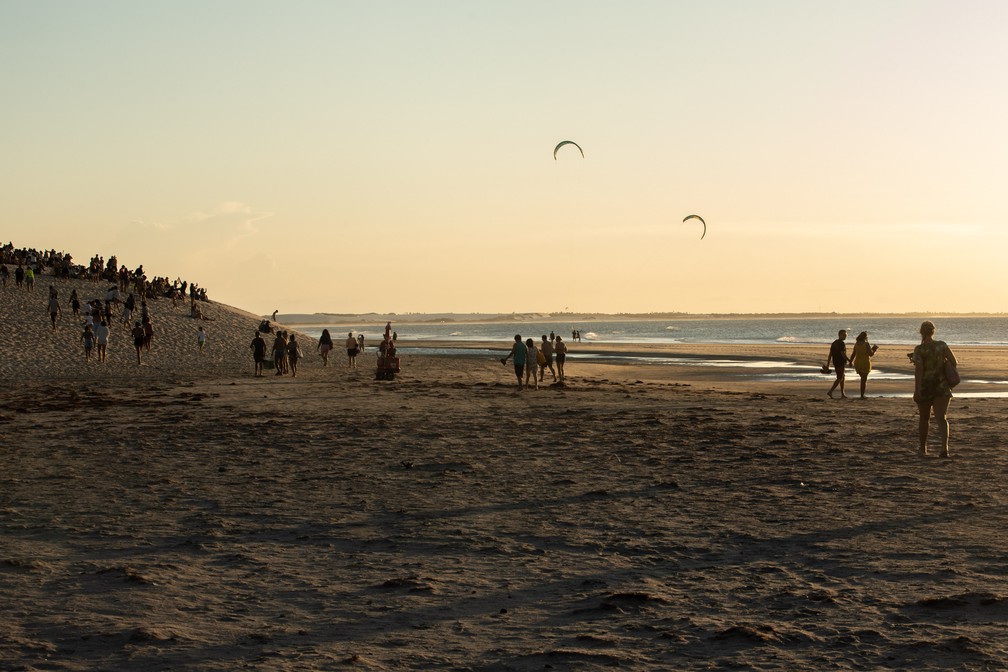 Com a aproximação do pôr do sol, turistas caminham até a duna da praia central — Foto: Celso Tavares/G1