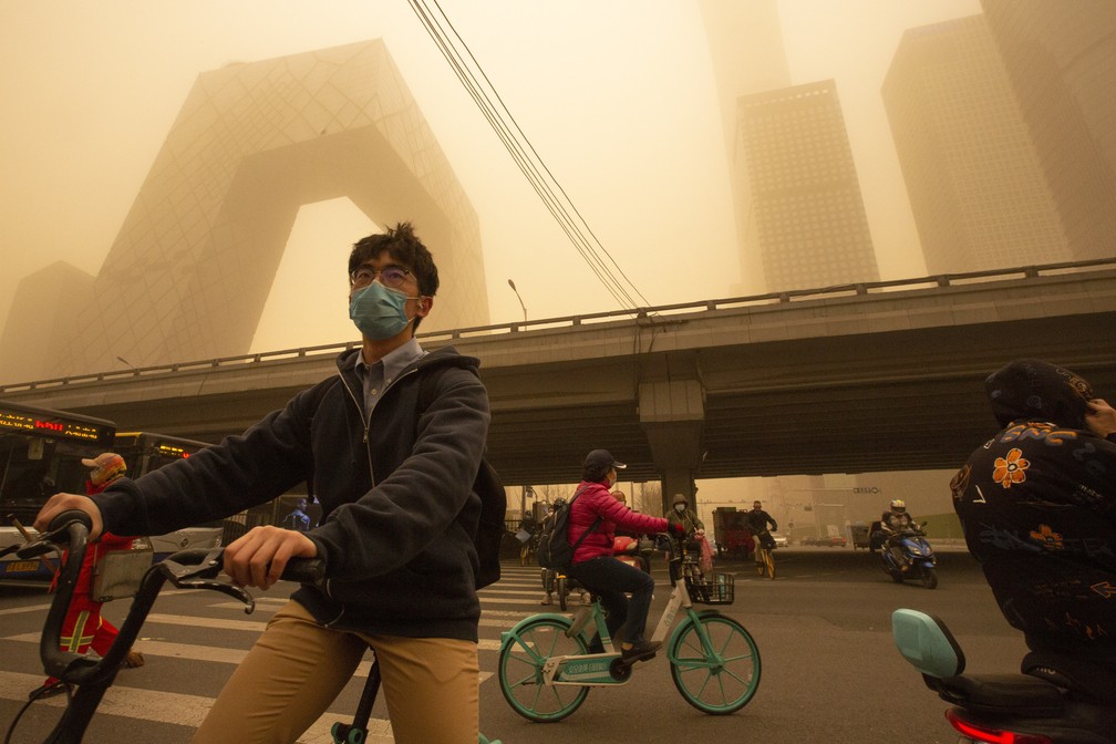 Ciclistas em meio a tempestade de areia durante o horário de rush no distrito comercial de Pequim nesta segunda-feira (15) — Foto: Mark Schiefelbein/AP