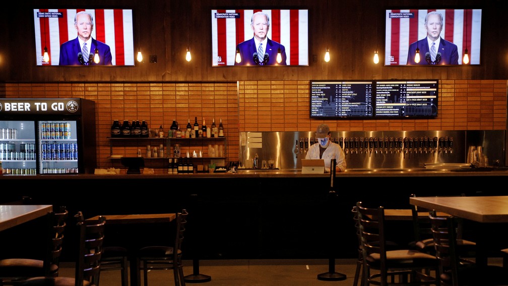 Televisões em cervejaria de Wisconsin mostram vídeos do candidato Joe Biden antes de discurso nesta quinta-feira (20) — Foto: Brian Snyder/Reuters