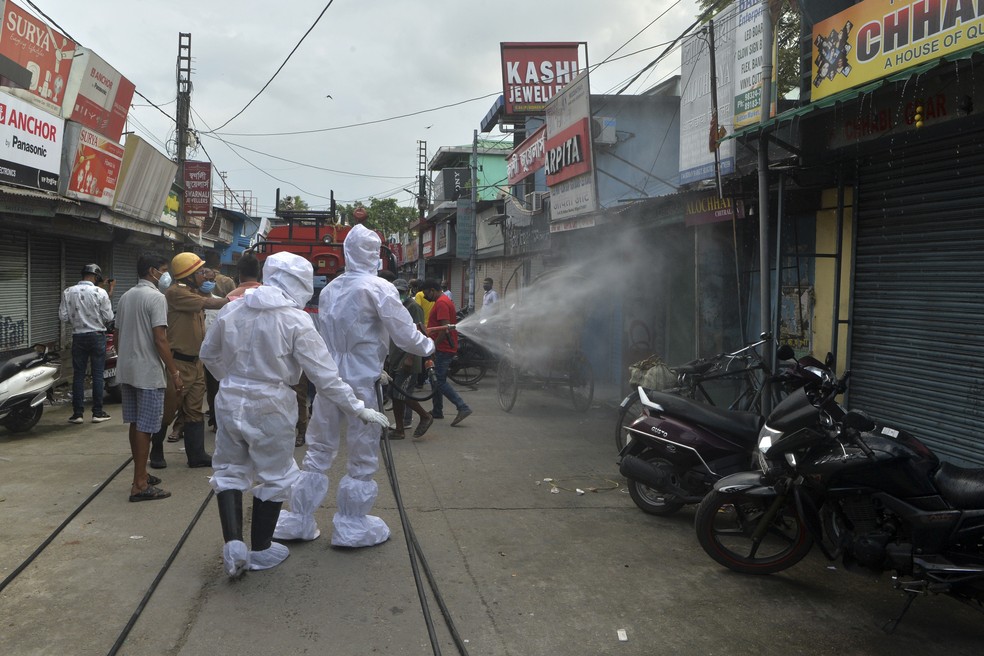 22 de junho: bombeiros usam spray desinfetante em lojas fechadas de um mercado em Shiliguri, na Índia, contra a Covid-19. — Foto: Diptendu Dutta / AFP