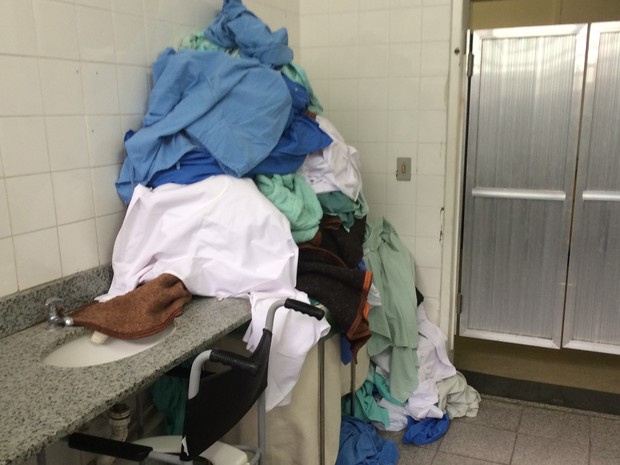 Roupas hospitalares acumuladas no banheiro onde os acompanhantes dos pacientes tomam banho (Foto: Cristina Boeckel/ G1)