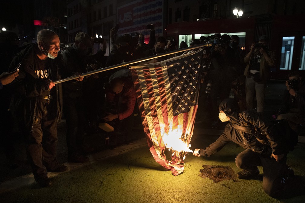 Manifestantes queimam bandeira durante protesto em Portland, Oregon, nesta quarta-feira (4) — Foto: Paula Bronstein/AP