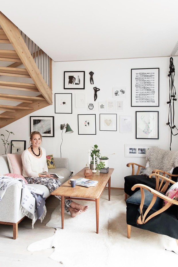 Niki em sua sala com tapete que imita pele e uma manta, itens indispensáveis para quem quer decorar com estilo escandinavo  (Foto: Divulgação)