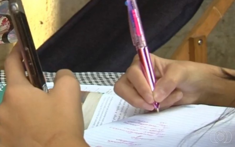Aluna estuda pelo celular enquanto aulas presenciais estão suspensas em Goiás — Foto: Reprodução/TV Anhanguera