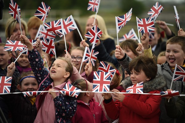 Um grupo de crianças celebrando a visita da Rainha Elizabeth 2ª e da atriz Meghan Markle (Foto: Getty Images)