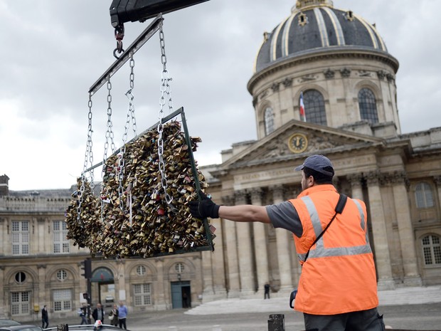 Um trabalhador remove os &#39;cadeados do amor&#39; da Pont des Arts em Paris, na França. O ritual começou com turistas em 2008 e logo se espalhou para cidades como Nova York, Seul e Londres. Cerca de 1 milhão de cadeados pesando 45 toneladas serão removidos (Foto:  Stephane De Sakutin/AFP)