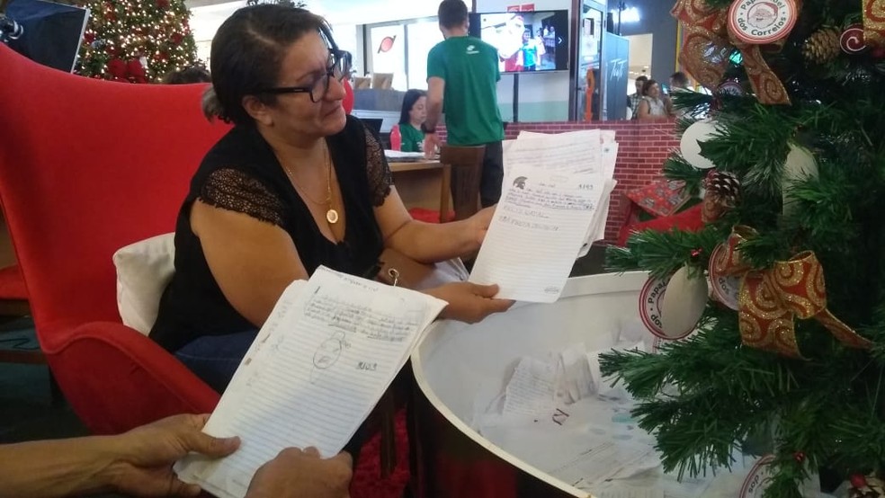 Casal Flávio Henrique e Rosiane de Araújo adotou mais de 15 cartinhas no escritório do Papai Noel, em Maceió — Foto: Matheus Tenório/G1