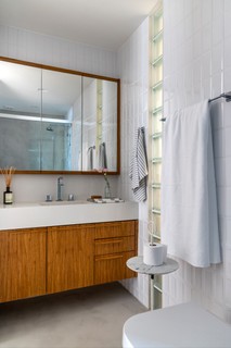 A arquiteta Paula Neder e o Cotetivo PN+ criaram um banheiro com contraste entre tons claros e a madeira escura, conferindo aconchego ao ambiente