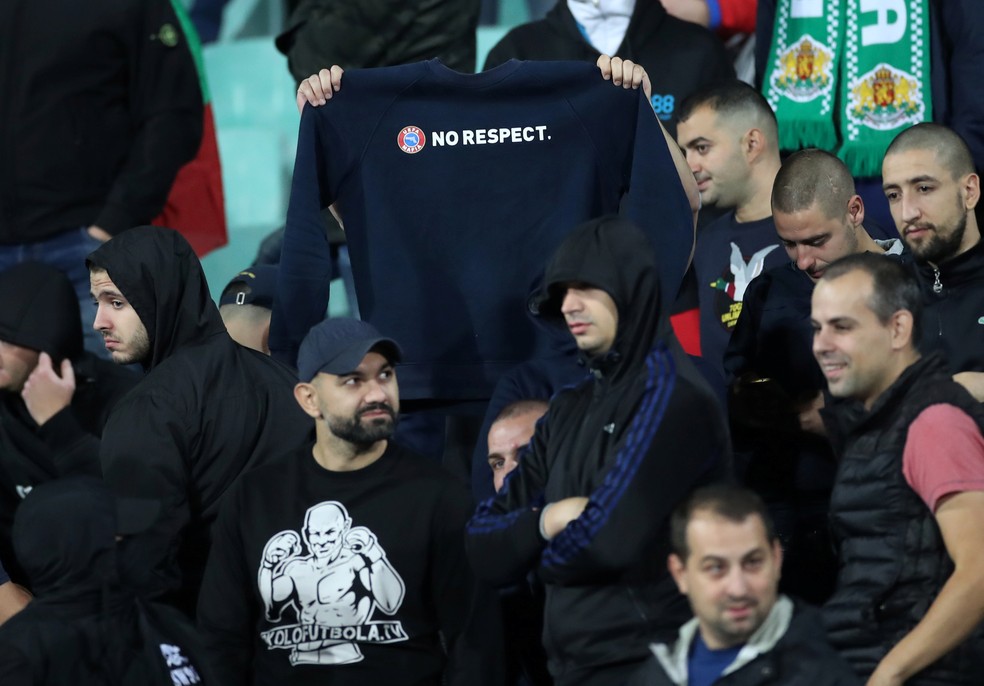 Torcedor ergue casaco com provocação a slogan da Uefa em que pede respeito — Foto: Carl Recine/Reuters