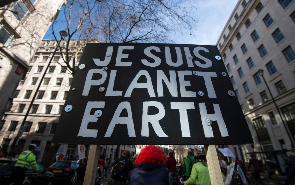 Uma placa com os dizeres 'Eu sou o planeta Terra' é vista durante a marcha pelo clima em Londres, na Inglaterra. A mensagem faz referência ao slogan 'Je suis Charlie' (Eu sou Charlie) usado após os ataques à revista francesa Charlie Hebdo (Foto: Niklas Hallen/AFP)