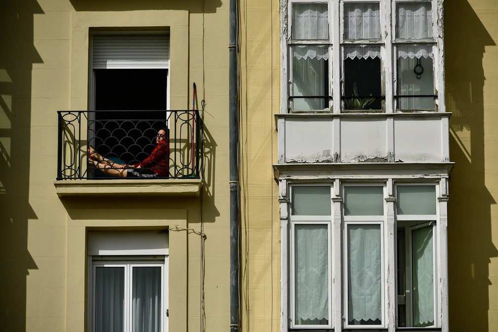 Uma mulher descansa na varanda de um prédio durante o isolamento para impedir a propagação do novo coronavírus em Vitória, no norte da Espanha, em 19 de março  — Foto:  Alvaro Barrientos/AP