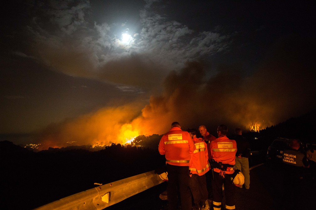 Bombeiros e policiais  olham para um pico em chamas na ilha de Gran Can&Atilde;&iexcl;ria, em agosto de 2019 &acirc; Foto: Desiree Martin/AFP