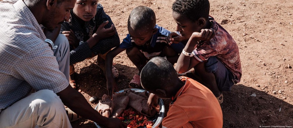 Crianças que fugiram do conflito no Tigré recebem comida em campo de refugiados no Sudão; região na Etiópia é palco de uma guerra entre governo e forças rebeldes desde novembro de 2020 — Foto: Yasuyoshi Chiba/AFP/Getty Images