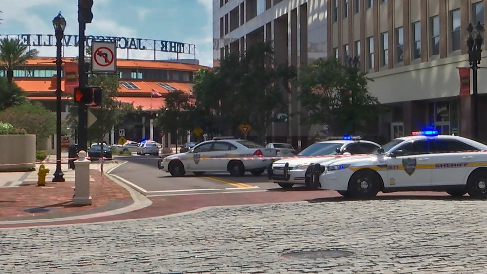 Carros da polícia bloqueiam uma rua que conduz à área de Jacksonville Landing, no centro de Jacksonville, na Flórida (Foto: HO/Courtesy of WJXT/AFP)