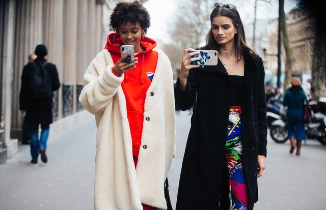 PARIS, FRANCE - JANUARY 24:  Brazilian models Samile Bermannelli, Linda Helena take photos of photographers on their cell phones after the Elie Saab show on January 24, 2018 in Paris, France. Samile wears a long white teddy bear coat, red Adidas hoodie, a (Foto: Getty Images)