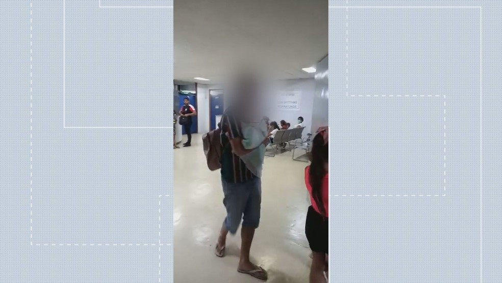 Homem com bebê de colo se irrita com demora no atendimento no Hospital do Guará, no DF — Foto: TV Globo/Reprodução