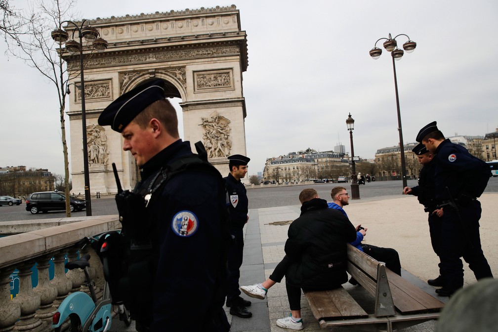Policiais conversam com turistas na avenida Champs-Elysées, em Paris, nesta terça-feira (17) Governo francês determinou confinamento por 15 dias — Foto: Christophe Ena/AP 