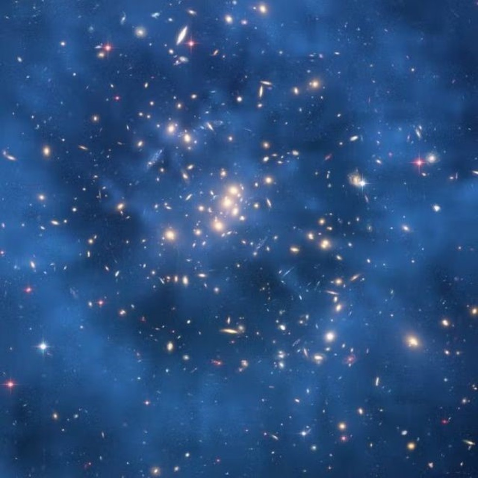 O anel de matéria escura modelado computacionalmente nesta imagem abrange cerca de cinco milhões de anos-luz e foi sobreposto digitalmente à imagem ao fundo, em azul difuso. Essa formação aconteceu quando duas galáxias colidiram — Foto: NASA, ESA, MJ JEE Y H. FORD ET AL. (JOHNS HOPKINS)