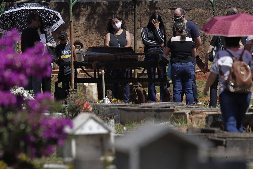 Familiares lamentam a morte de David Ferreira Gomes, que morreu devido a complicações relacionadas à Covid-19, durante enterro no cemitério Campo da Esperança, em Brasília, na sexta-feira (16) — Foto: Eraldo Peres/AP
