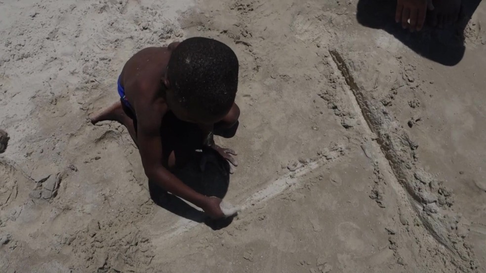 Menino refugiado brinca na areia de Copacabana (Foto: Reprodução/BBC Brasil)
