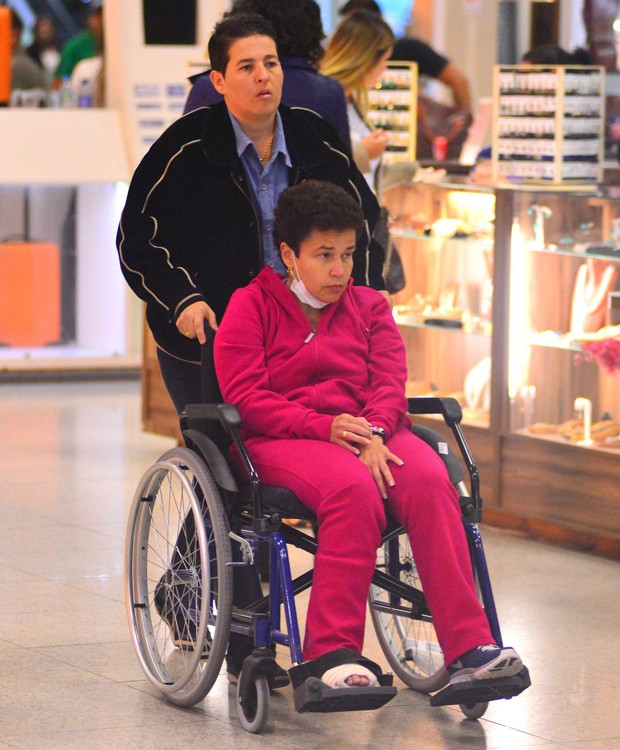 Auxiliada pela empresária Adriane Bonatto, Cadia Rodrigues se locomove em cadeira de rodas em aeroporto (Foto: William Oda / AgNews)