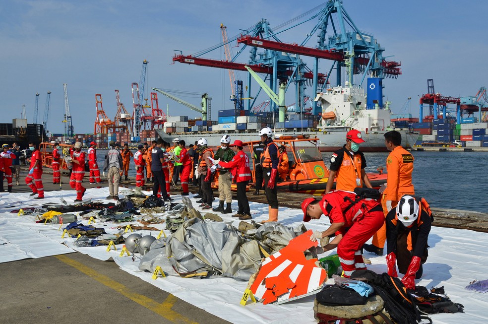 Membros da equipe de resgate organizam destroços do avião que caiu na Indonésia, mostrando parte do logotipo da Lion Air  — Foto: Stringer/Reuters