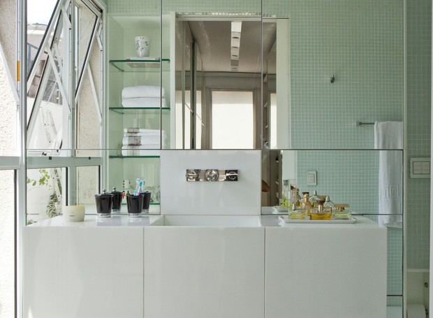 No projeto de Simone Mantovani, o banheiro de tons claros e com parede de espelhos dá a sensação de amplitude. Repare que a bancada suspensa com gavetões otimiza o espaço. (Foto: Edu Castello / Casa e Jardim)