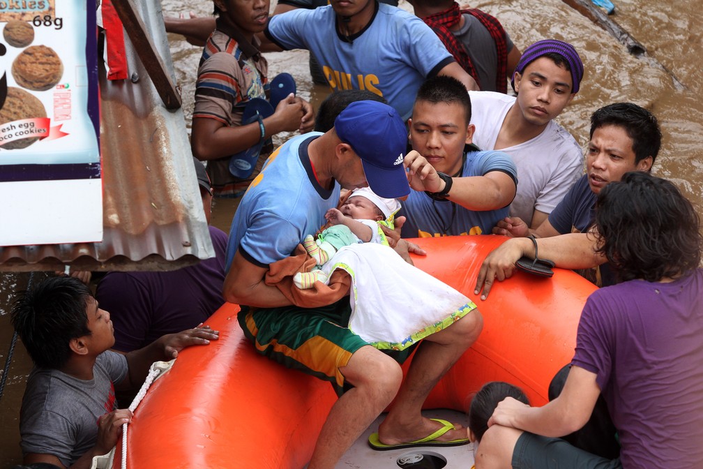 Policial salva bebê na cidade de Cagayan nesta sexta-feira, 22, em tempestade tropical nas Filipinas (Foto: Messan Annam/AFP )