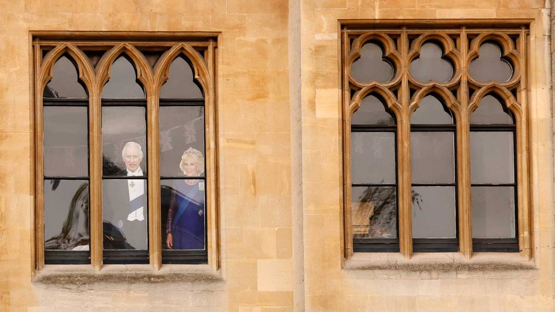 Rei Carlos III e a rainha Camilla na janela de um prédio com vista para a Abadia de Westminster, no centro de Londres