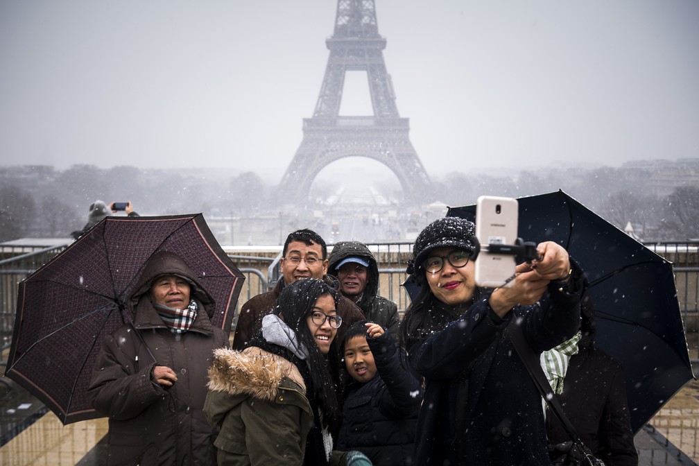Foto de arquivo mostra turistas fazendo selfie na neve diante da Torre Eiffel em Paris — Foto: Lionel Bonaventure/AFP