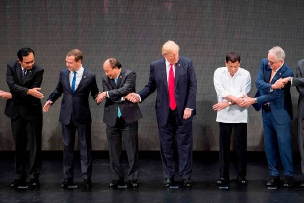 O ex-presidente dos EUA, Donald Trump, ficou brevemente surpreso quando os líderes foram convidados a cruzar as mãos em uma cúpula nas Filipinas em 2017 — Foto: JIM WATSON/AFP VIA GETTY IMAGES/BBC