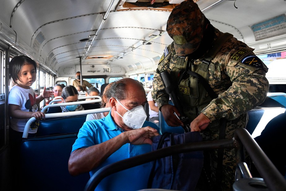 Um soldado verifica os pertences de um passageiro dentro de um ônibus durante uma operação contra membros de gangues, em Soyapango