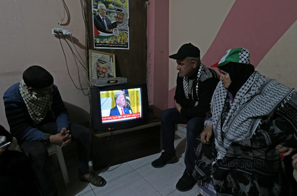 Palestinos na Faixa de Gaza assistem a discurso de Donald Trump sobre plano de paz com Israel nesta terça-feira (28) — Foto: Ibraheem Abu Mustafa/Reuters