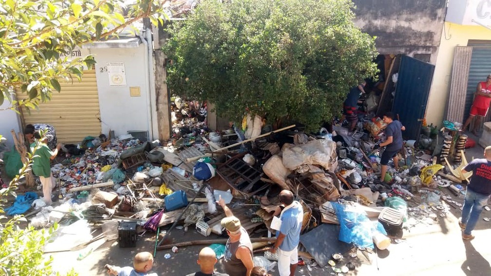 Lixo retirado pelas equipes ficou temporariamente espalhado pela rua até ser removido — Foto: Claudia Assencio/ g1