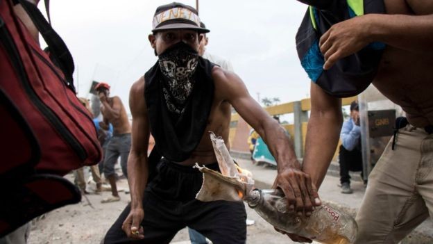 Homens encapuzados protestam durante tentativa de entrada de ajuda humanitária na Venezuela, no fim de semana (Foto: NURPHOTO via BBC)