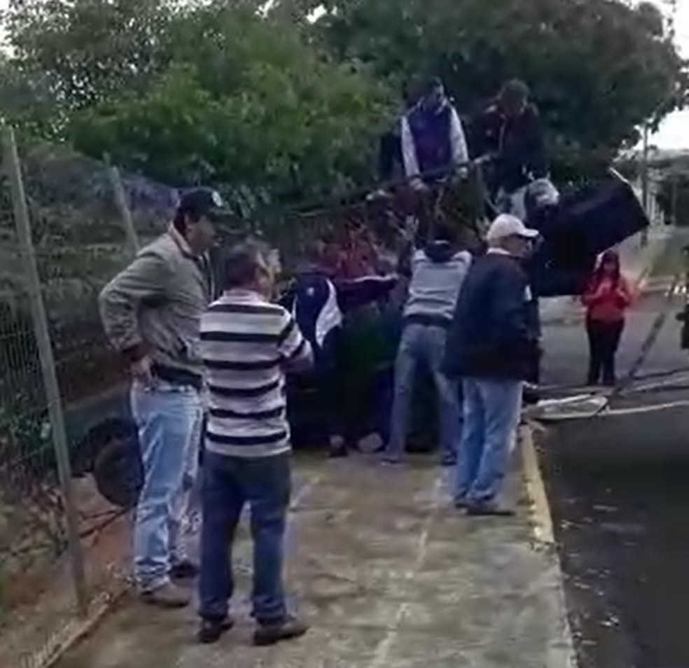 Pessoas que passavam pelo local seguravam o carro, que ficou 'pendurado' â Foto: Cedida/Devair Miranda