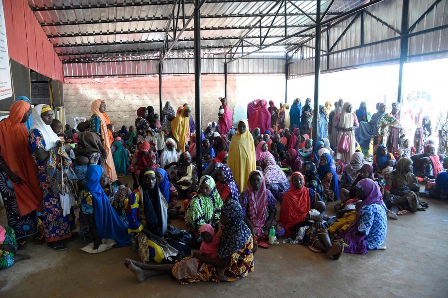 Mães sentadas no chão com crianças que sofrem de desnutrição em uma clínica montada por autoridades de saúde em colaboração com Médicos Sem Fronteiras (MSF), no estado de Katsina, na Nigéria
