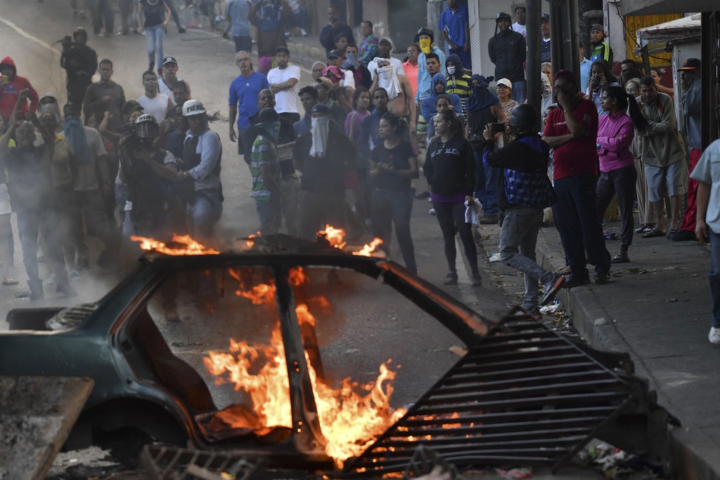 Manifestantes queimam carro em protesto em torno da sede da Guarda Nacional Bolivariana de Cotiza, na Venezuela, onde um grupo de militares se rebelou contra Maduro â€” Foto: Yuri Cortez / AFP