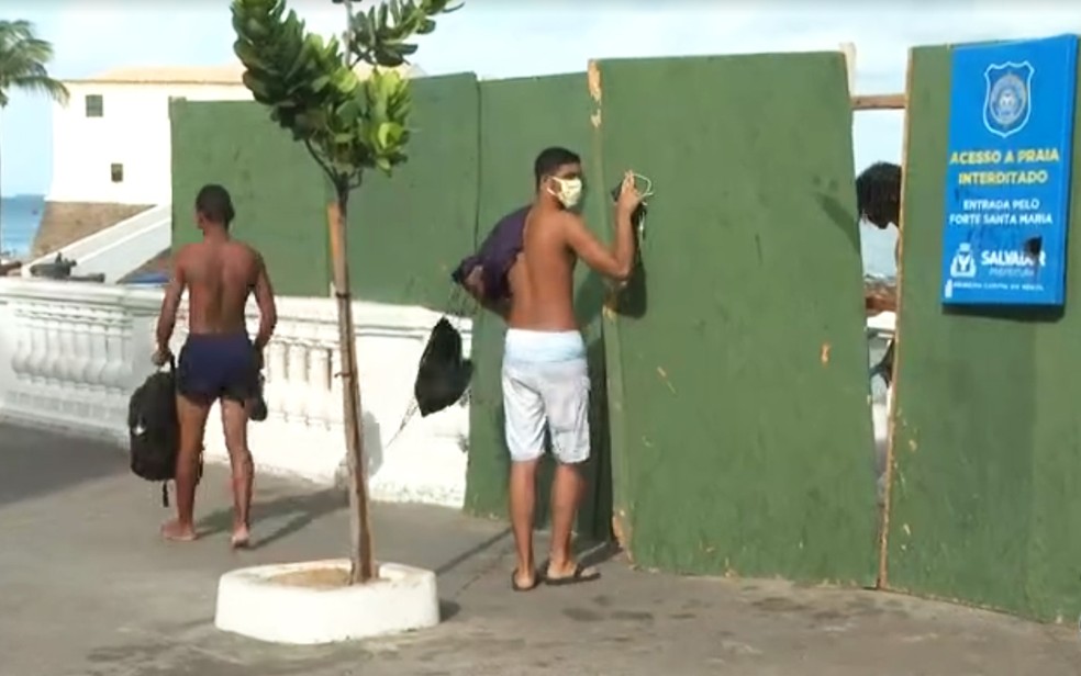 Banhistas abriram tapumes para terem acesso a trecho da praia do Porto da Barra — Foto: Reprodução/TV Bahia