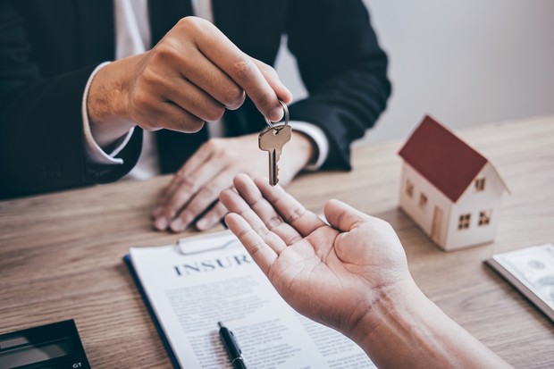 Estate agent giving house keys to client after signing agreement contract real estate with approved mortgage application form, concerning mortgage loan offer for and house insurance. (Foto: Getty Images/iStockphoto)