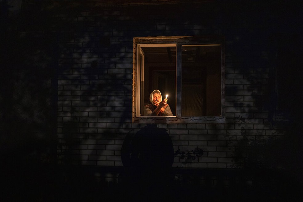 Mulher segura vela após cidade nos arredores de Kiev ficar sem luz por conta de ataques da Rússia, em 20 de outubro de 2022. — Foto: Emilio Morenatti/ AP