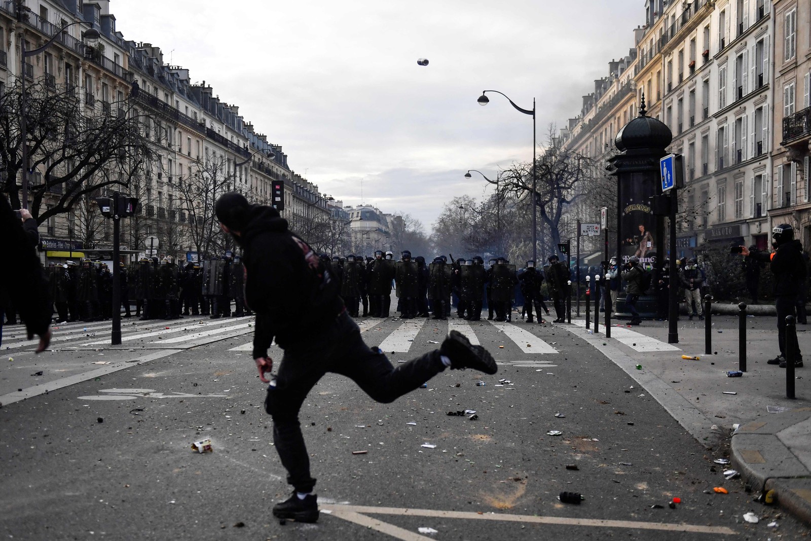 Manifestante atira uma lata em direção às forças de segurança durante manifestação em Paris — Foto: JULIEN DE ROSA / AFP