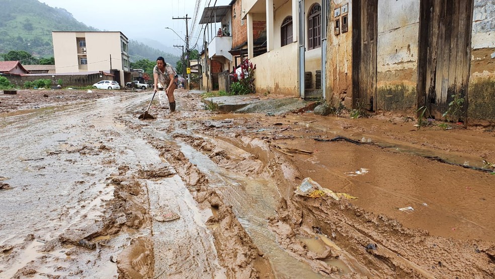 Moradora do bairro Ipanema, em Viana, usa enxada para limpar lama deixada na rua pela chuva — Foto: Carlos Alberto Silva/Rede Gazeta