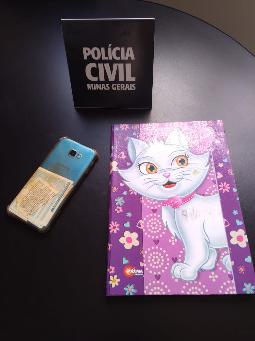 Celular do suspeito e caderno da vítima foram apreendidos — Foto: Polícia Civil/Divulgação 