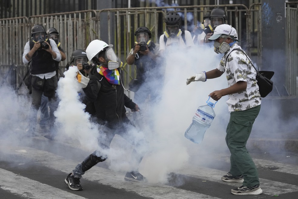 Os chamados ‘desativadores’ tentam para neutralizar uma bomba de gás lacrimogêneo durante um protesto em Lima, Peru, em 28 de janeiro de 2023 — Foto: Martin Mejia/AP