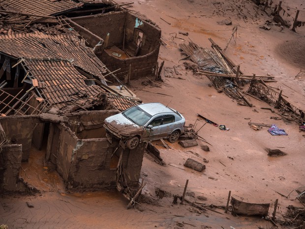 06/11 - Um carro é visto sobre os destroços de uma casa em meio a lama após o rompimento de uma barragem de rejeitos da mineradora Samarco no Distrito de Bento Rodrigues, no interior de Minas Gerais (Foto: Christophe Simon/AFP)