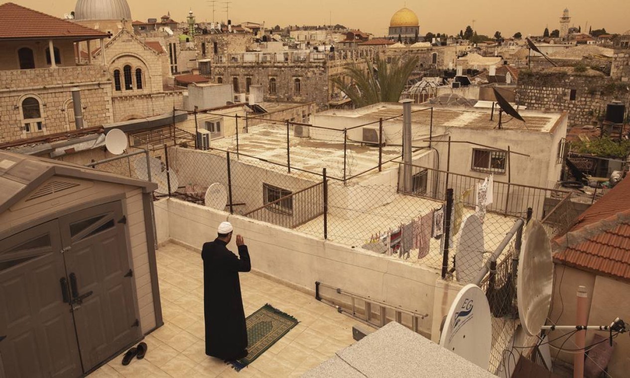 Homem ora em um telhado durante as orações da tarde do Ramadã em Jerusalém, em abril de 2020. A pandemia do coronavírus transformou como os muçulmanos em Israel e nos territórios palestinos estão experimentando a data sagrada — Foto: DAN BALILTY / The New York Times