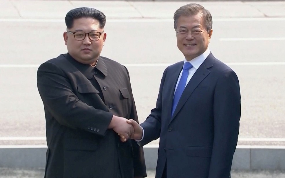 O líder norte-coreano Kim Jong-un cumprimenta o presidente sul-coreano Moon Jae-in ao chegar na Zona Desmilitarizada, em abril. (Foto: Host Broadcaster via Reuters)