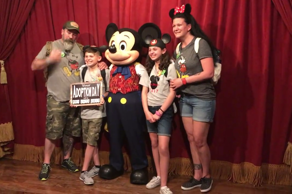 O personagem Mickey Mouse da Disney com a família emocionada com a notícia da adoção (Foto: Facebook)