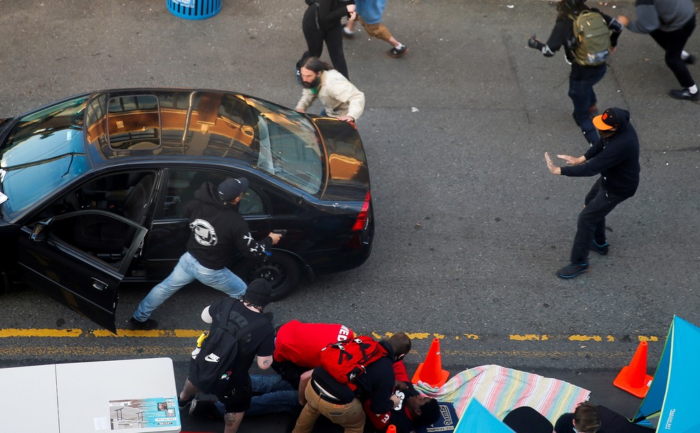 7 de junho - Um homem carregando uma arma sai de um veículo enquanto Daniel Gregory é atendido por médicos após ser baleado no braço por um motorista que tentou dirigir no meio de um protesto contra a desigualdade racial após a morte de George Floyd, em Seattle, Washington, nos EUA — Foto: Lindsey Wasson/Reuters